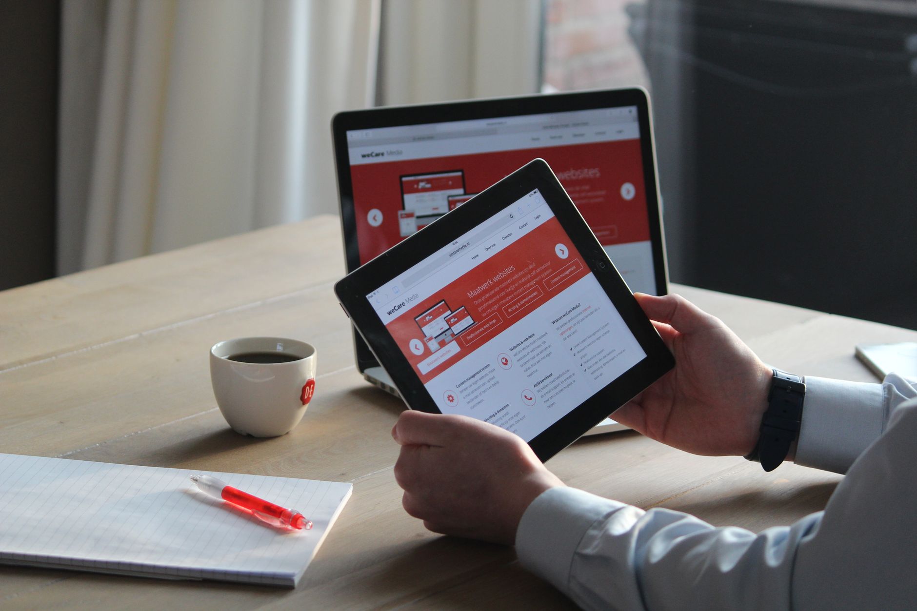 Business professional reviewing a service business website on a tablet and laptop at a desk