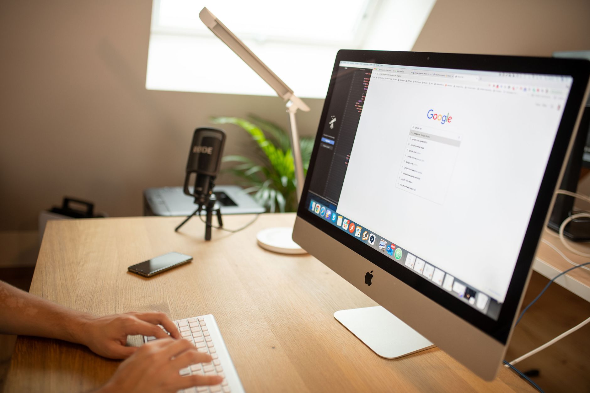 Person typing on keyboard with iMac displaying Google search engine, representing WordPress SEO setup and search optimization