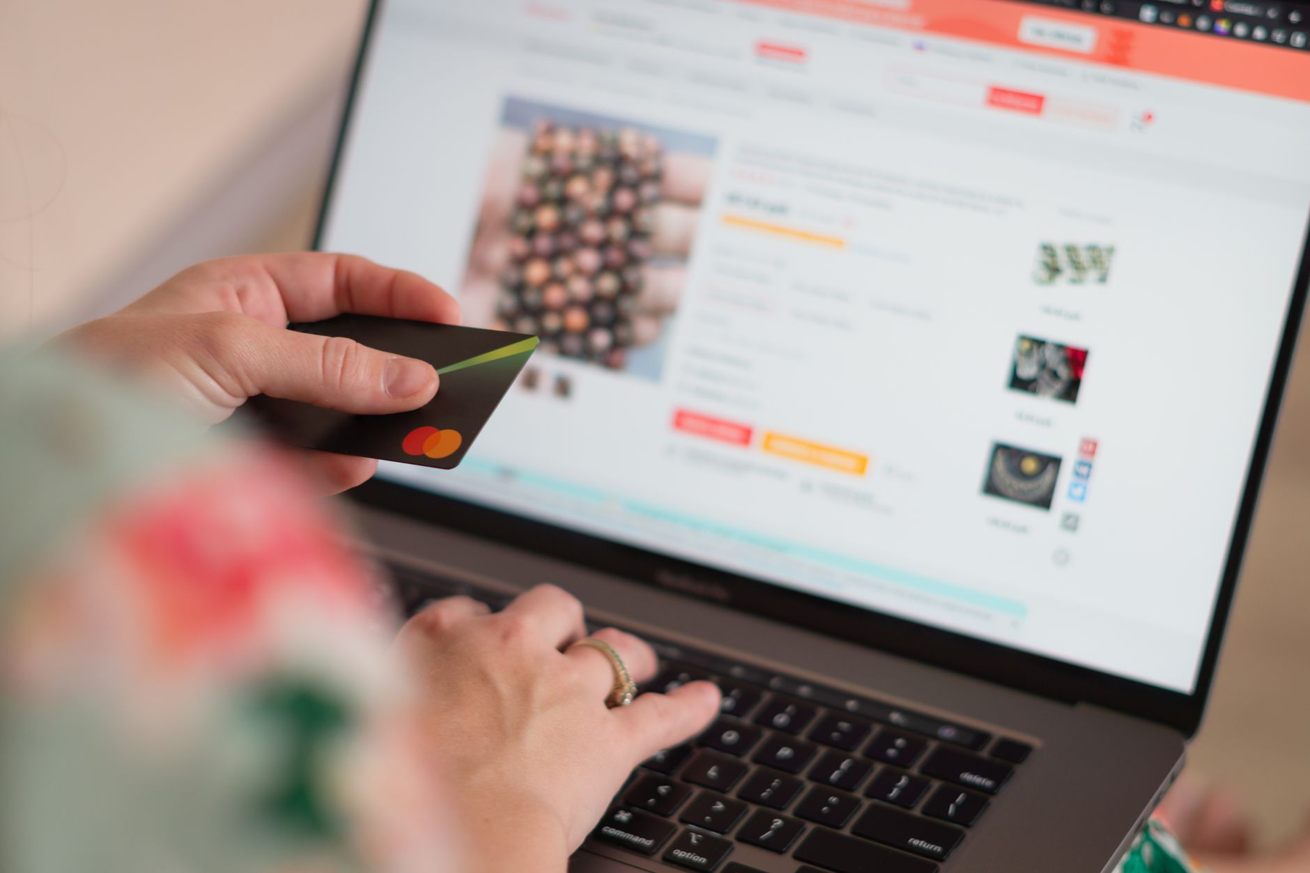 Person holding a credit card while reviewing an ecommerce product page on a laptop, illustrating trust and buying clarity
