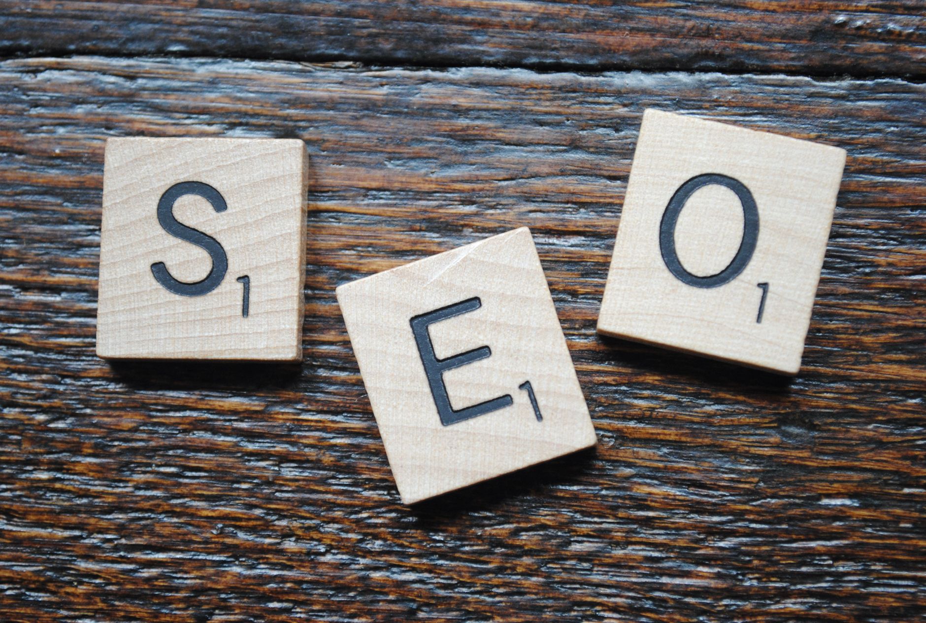 Close-up of Scrabble tiles spelling SEO on a wooden table, representing search engine optimization strategy