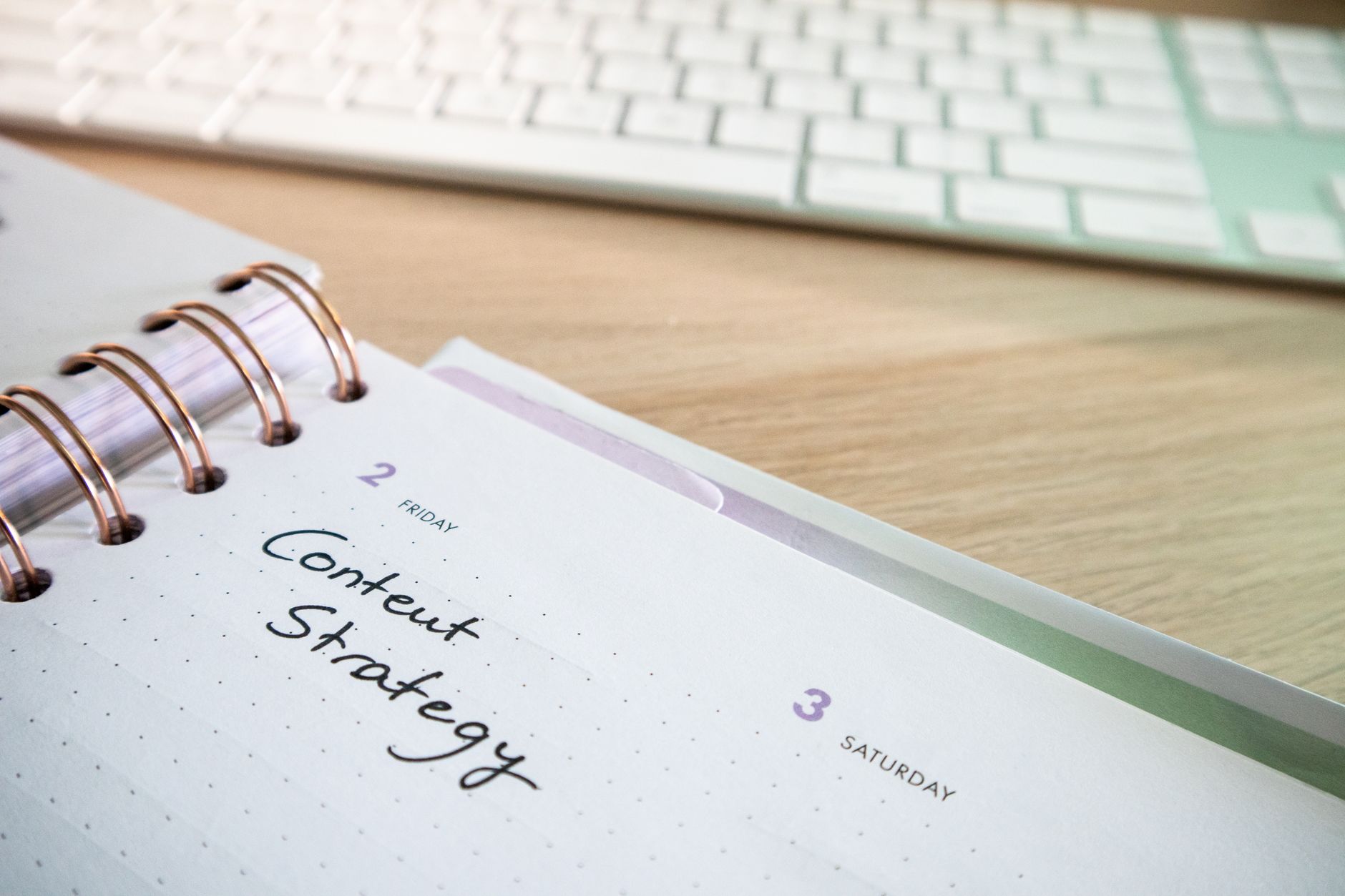 Content strategy written in a planner with keyboard on wooden desk, representing internal linking and content planning