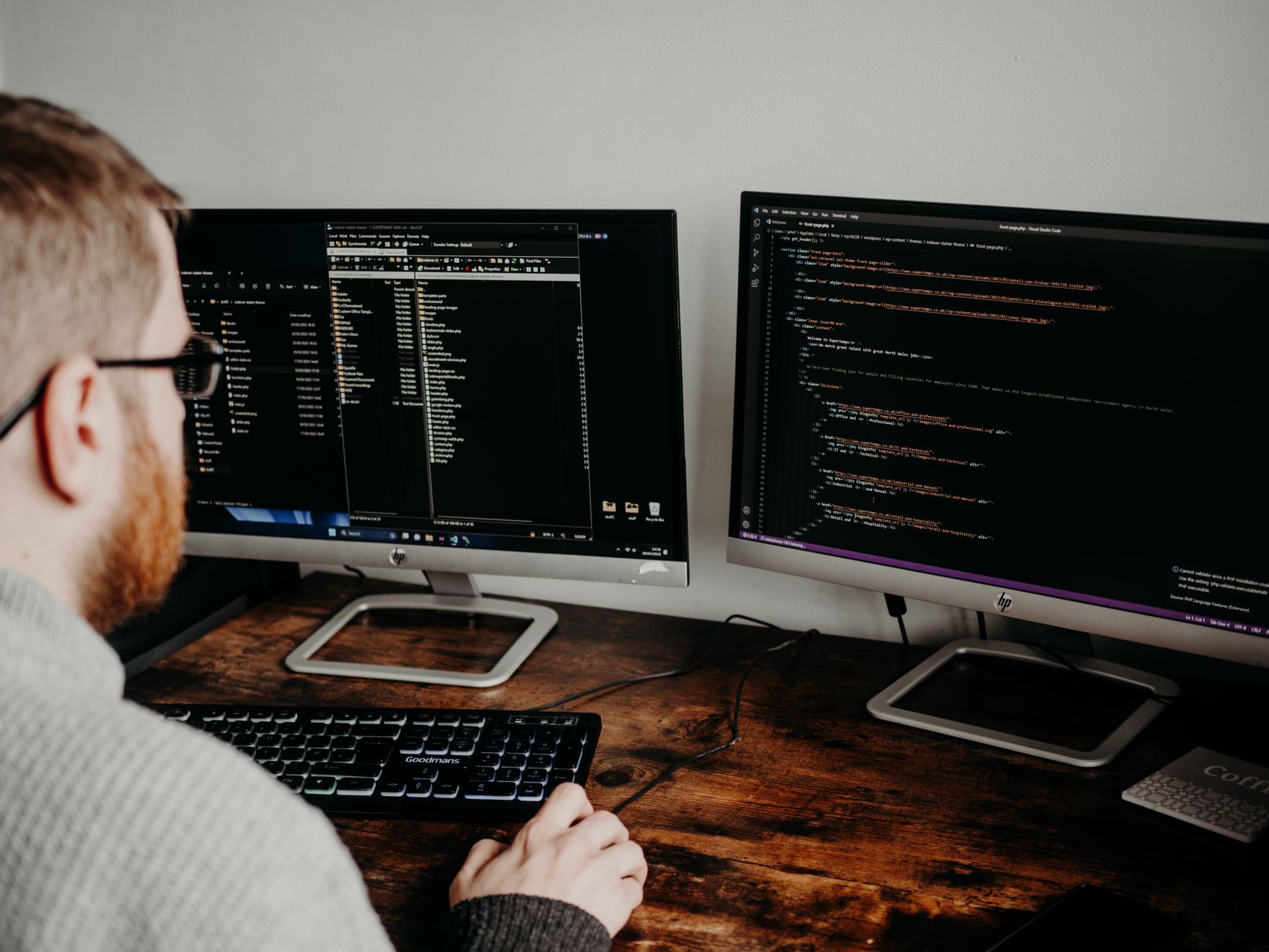Developer working on technical SEO audit with dual monitors showing code and site structure