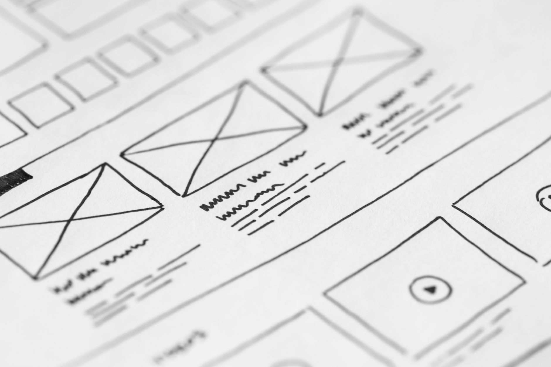 Hand-drawn wireframe layout sketched on paper showing website page structure with headings and content blocks