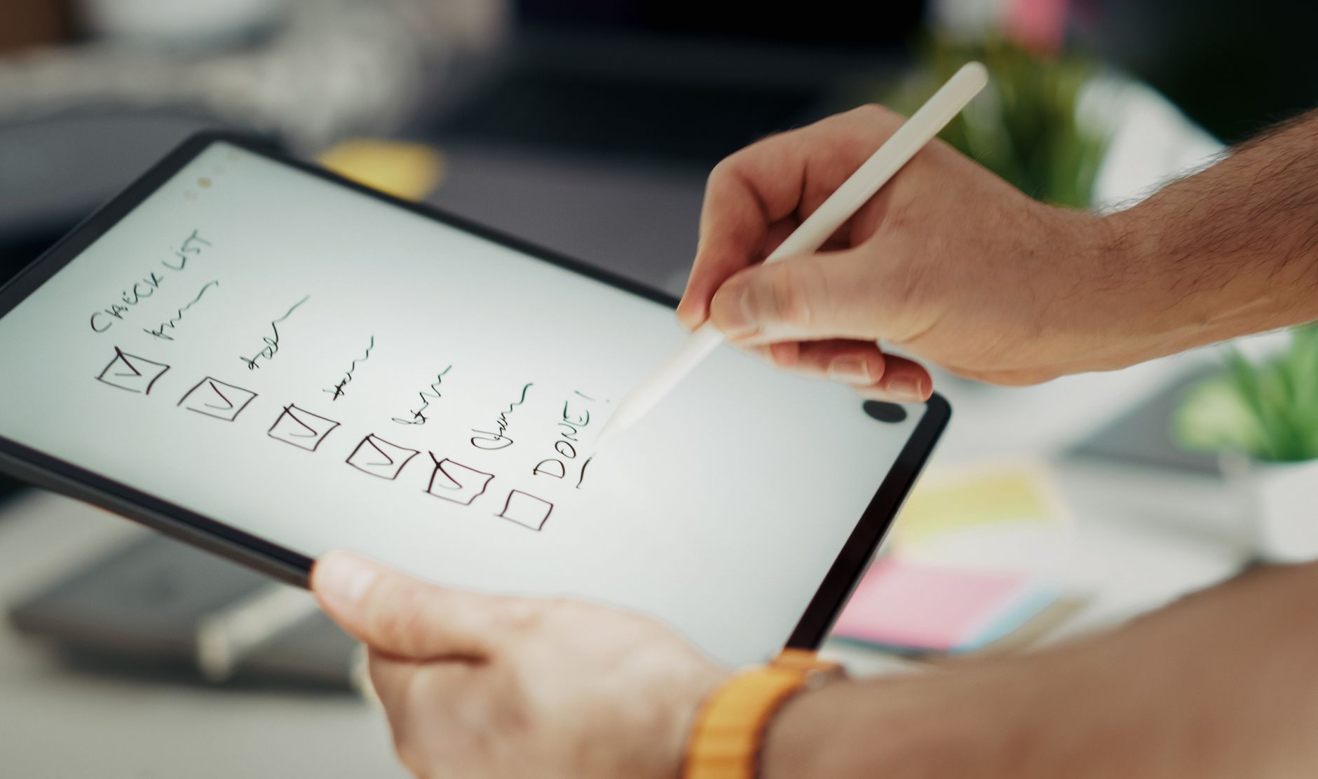 Close-up of a hand writing a checklist on a digital tablet using a stylus, representing a WordPress SEO checklist workflow
