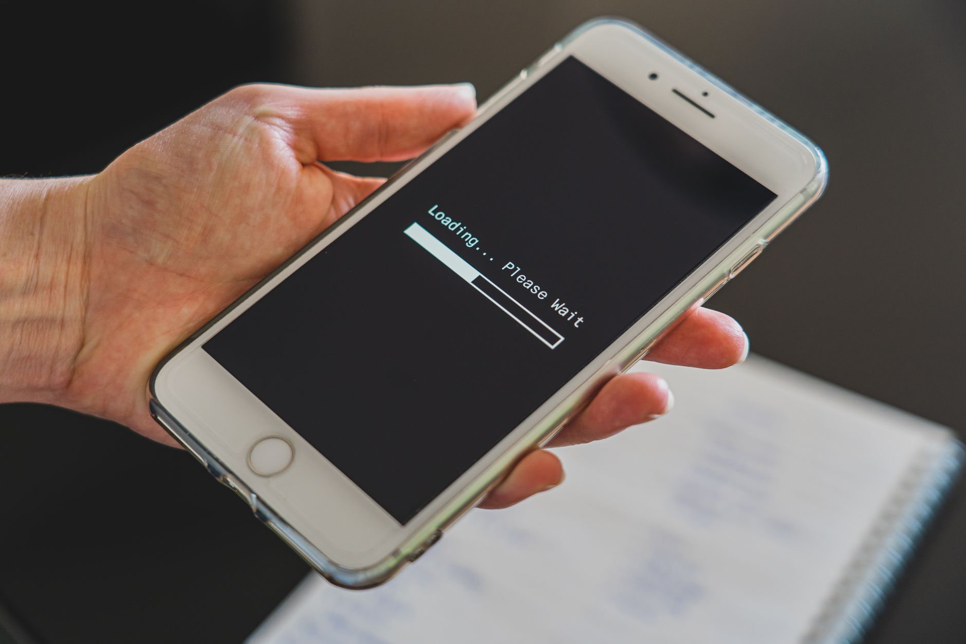 Hand holding a smartphone displaying a loading screen, representing slow website page speed on mobile