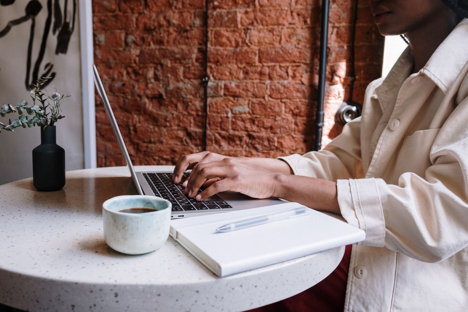 Person typing on a laptop with a notepad beside them, planning content strategy