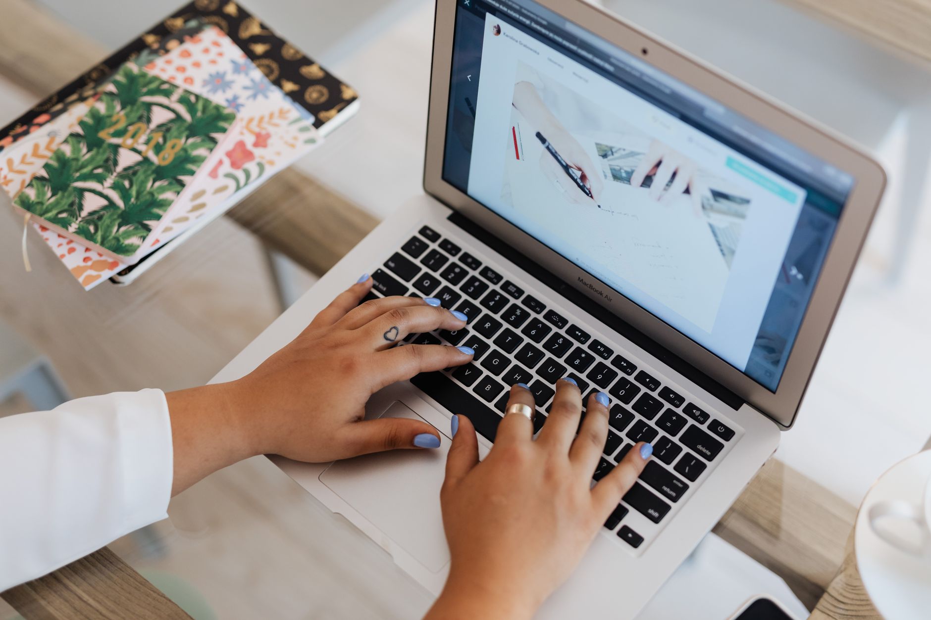 Hands typing on a laptop at a bright desk, creating helpful blog content for WordPress SEO