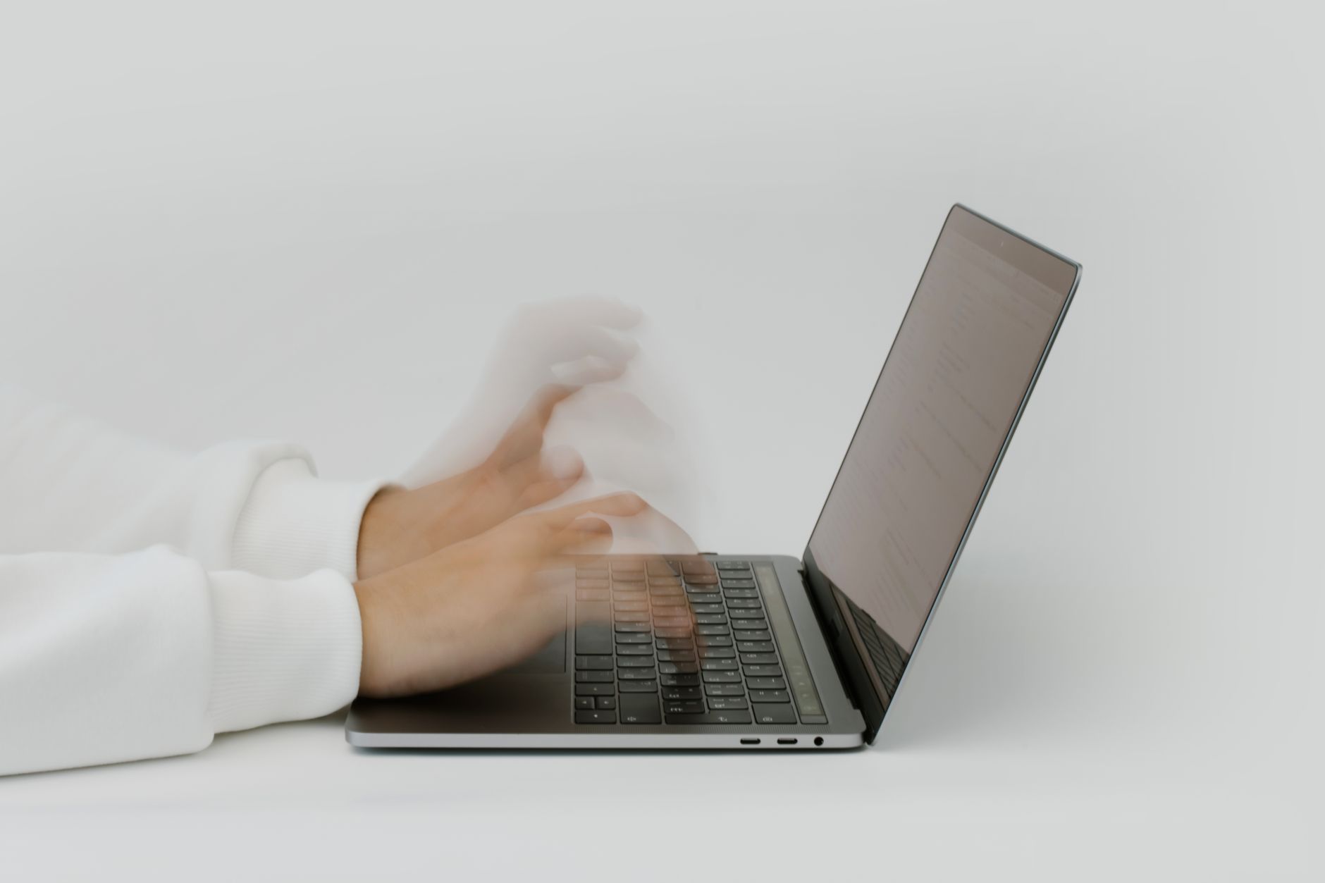 Motion-blurred hands typing rapidly on a laptop, symbolising website speed and fast page load performance for SEO.