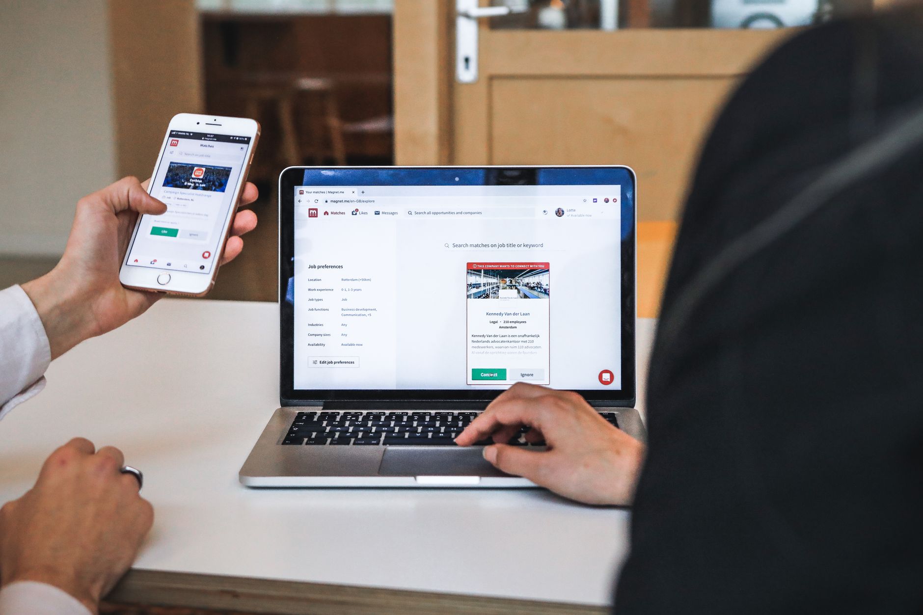 Person holding a smartphone next to a laptop, illustrating mobile and desktop internal linking strategy