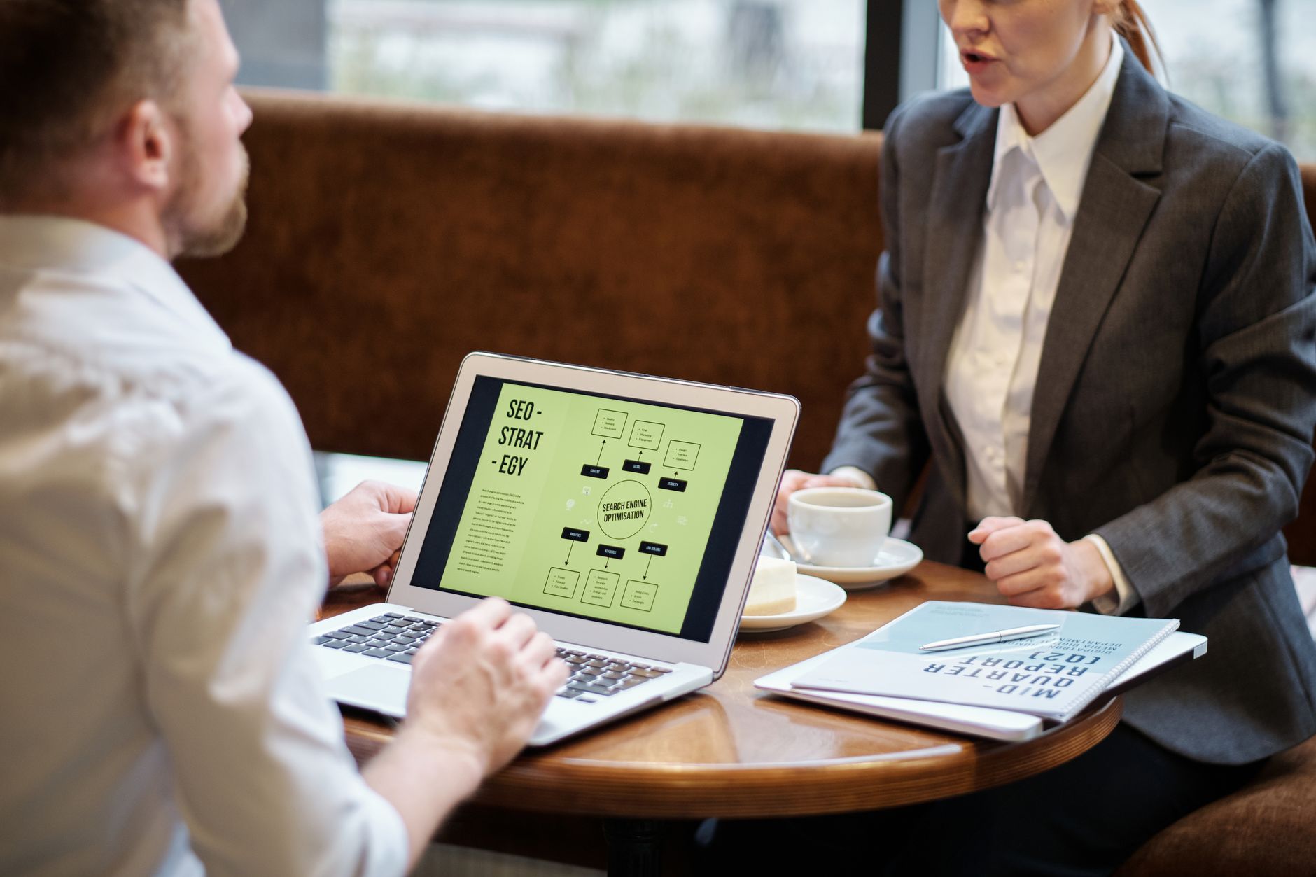 Two business professionals reviewing an SEO strategy presentation on a laptop screen