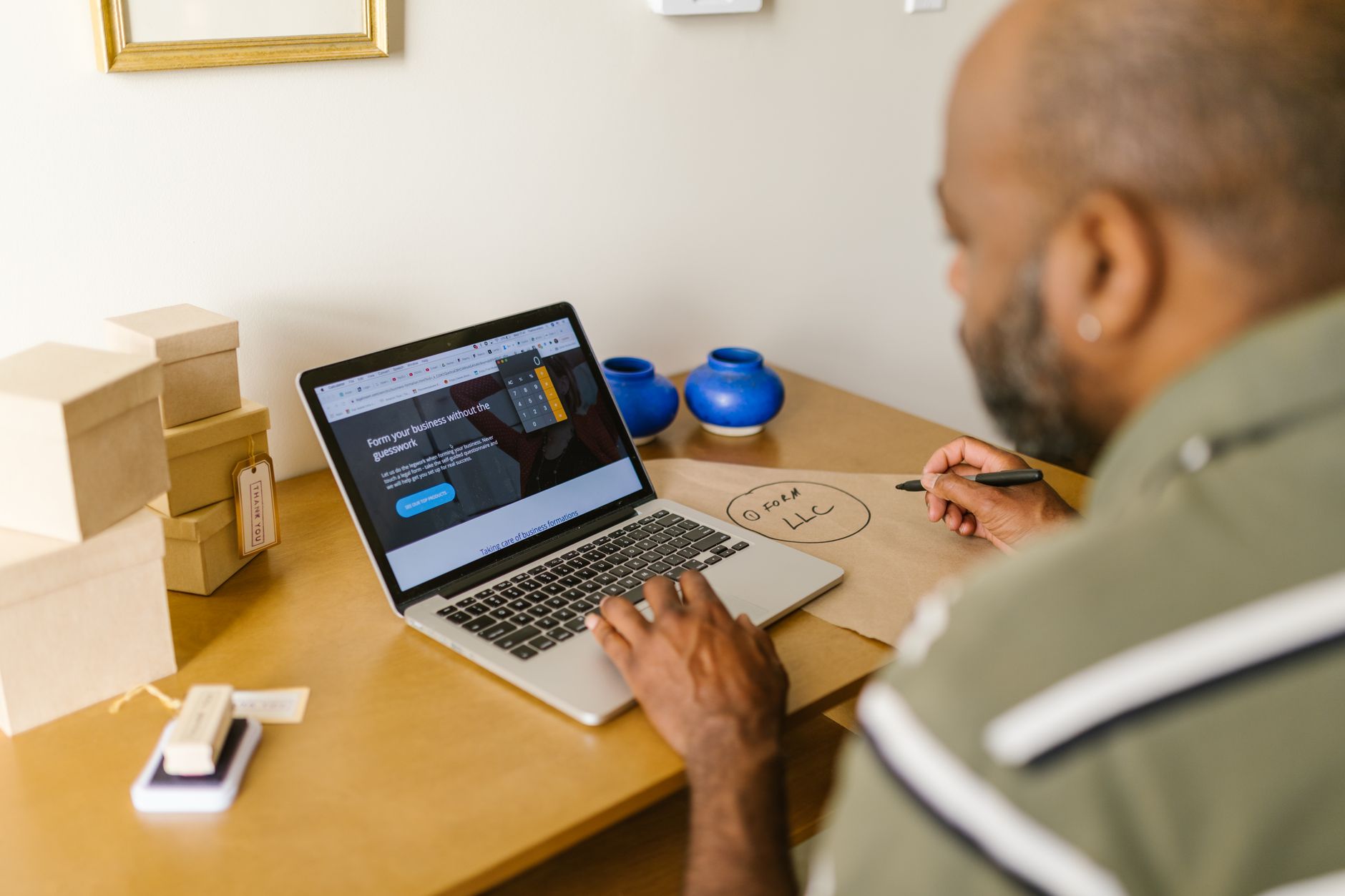 Small business owner working on a laptop with product packaging on the desk, planning website strategy