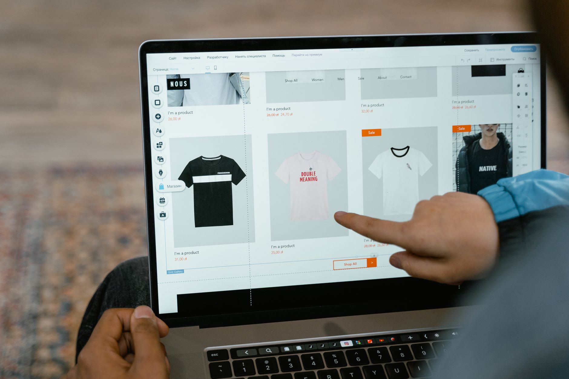 Person pointing at product categories on an ecommerce store displayed on a laptop screen