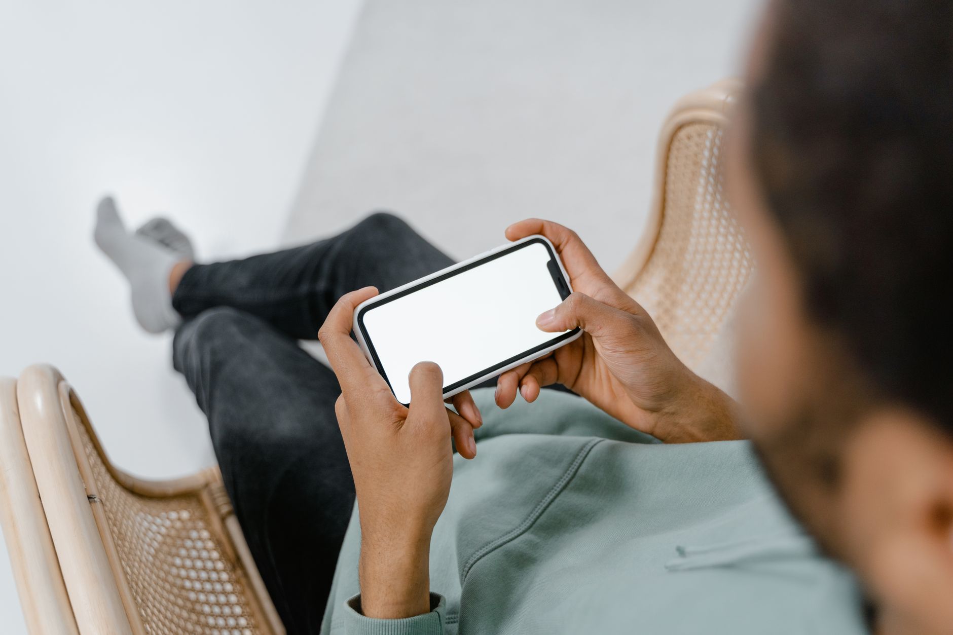 Person sitting in a chair holding a smartphone representing real device mobile usability testing