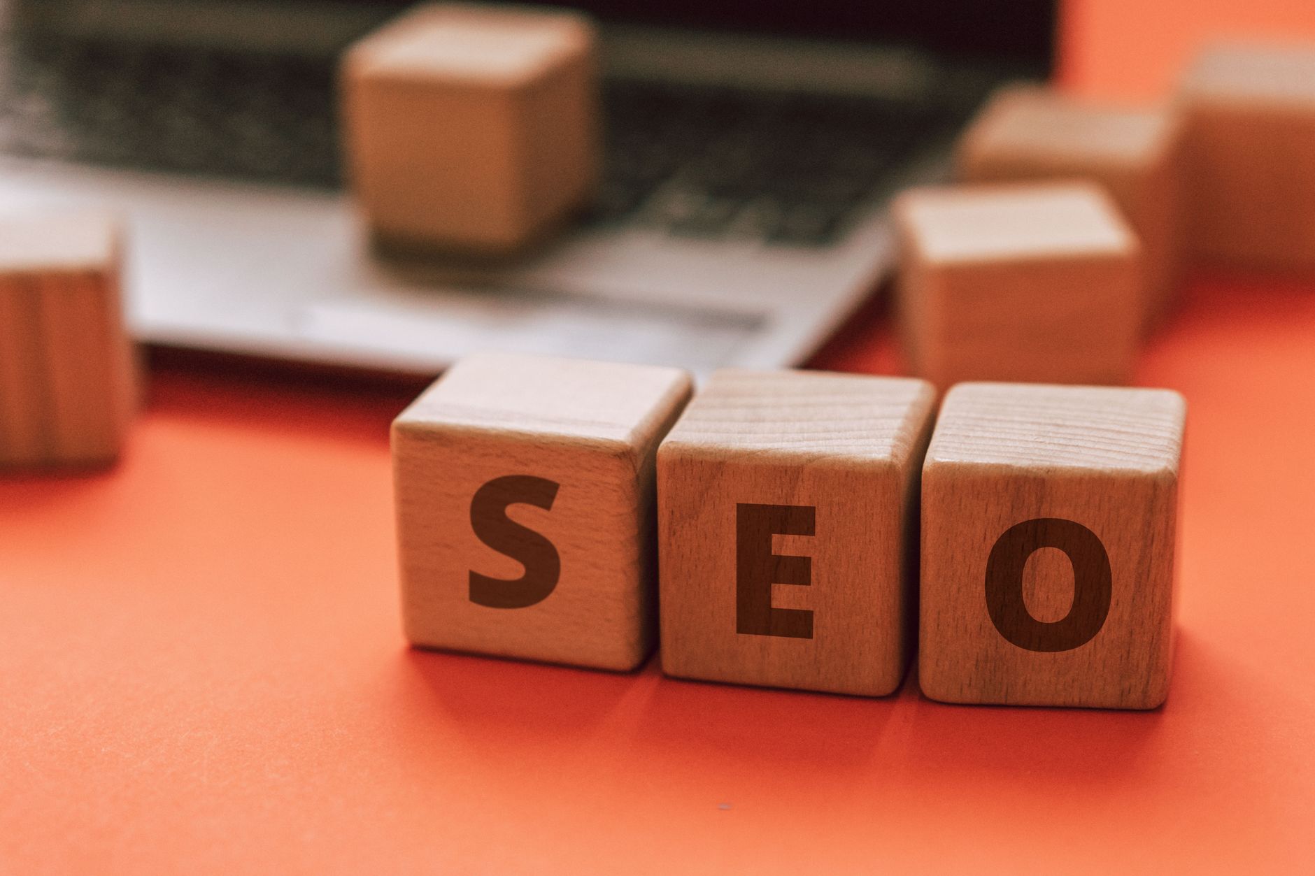 Wooden blocks spelling SEO next to a laptop representing WordPress SEO vs traditional SEO