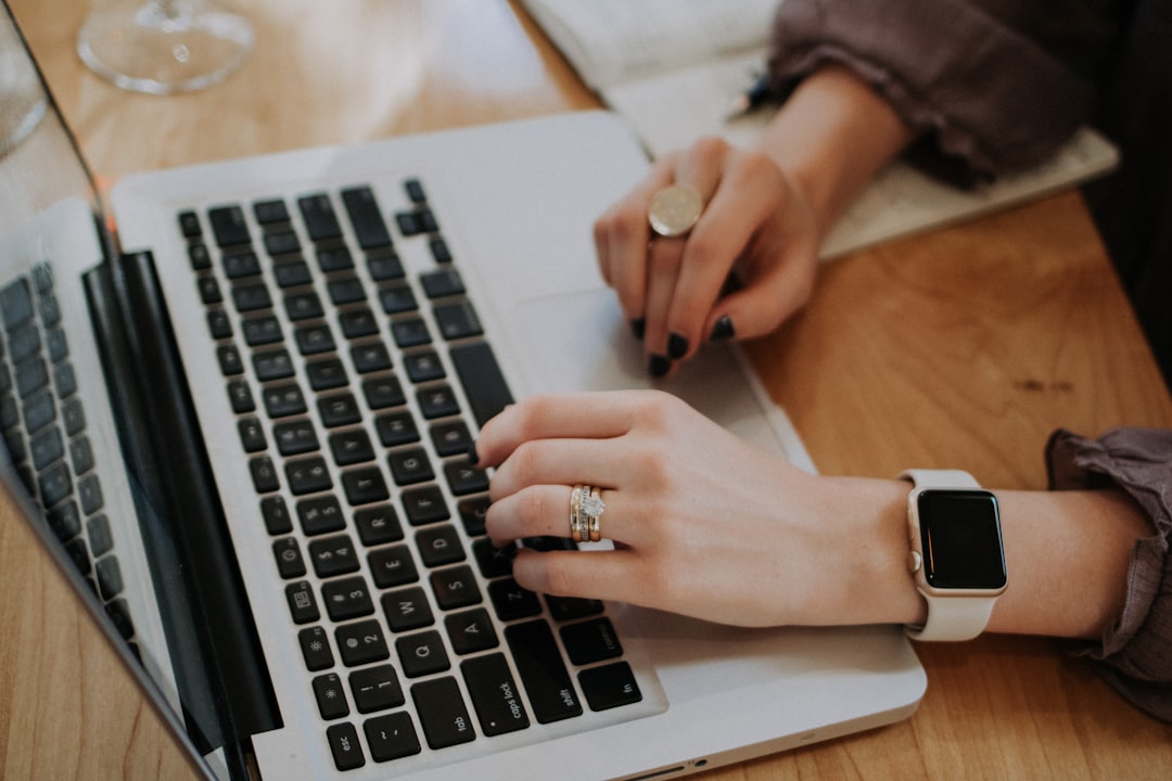 Person typing on a laptop while taking notes — editing page titles and meta descriptions for SEO