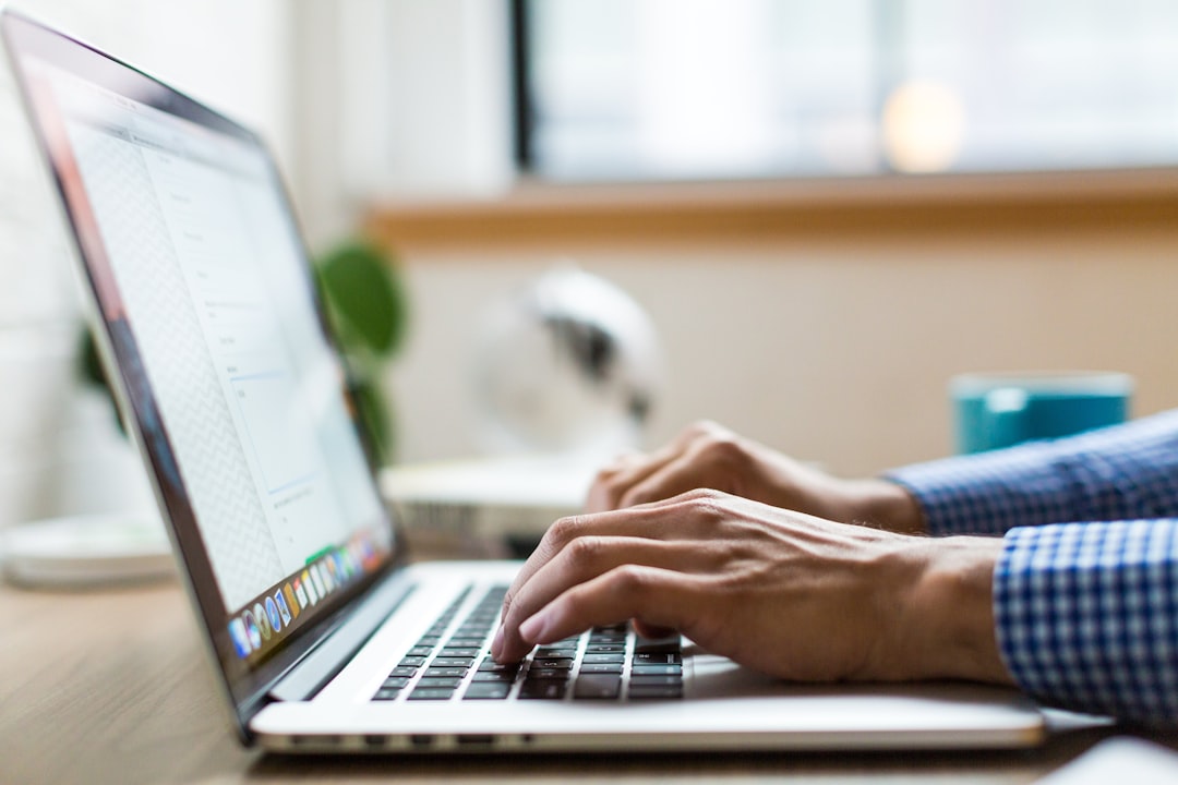 Person typing on a MacBook laptop writing SEO titles and meta descriptions