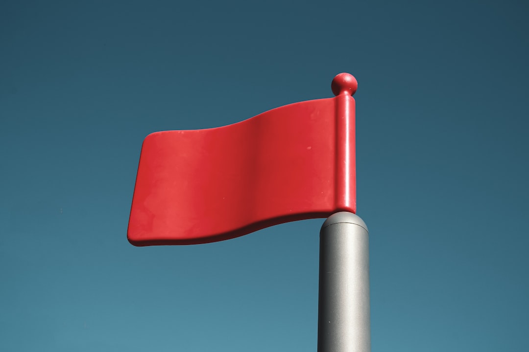 Red flag on a pole against a clear blue sky, symbolizing warning signs in link building services